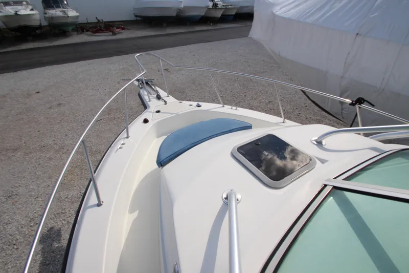Slide: The Image of 2002 Hydra-Sports 230 WA boat deck with railing and hatch, parked on gravel. - 15