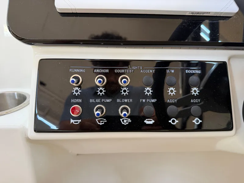 Slide: The Image of Close-up of a control panel with various switches and indicator lights on a Sea Ray SDX 230 boat. - 29