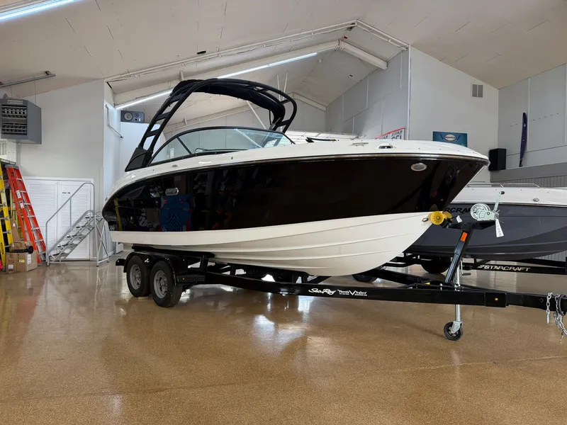 Slide: The Image of A 2026 Sea Ray SDX 230 boat on a trailer in a showroom. - 2