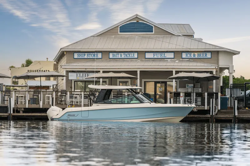 Slide: The Image of A 2027 Boston Whaler 330 Vantage docked in front of a waterside store. - 3