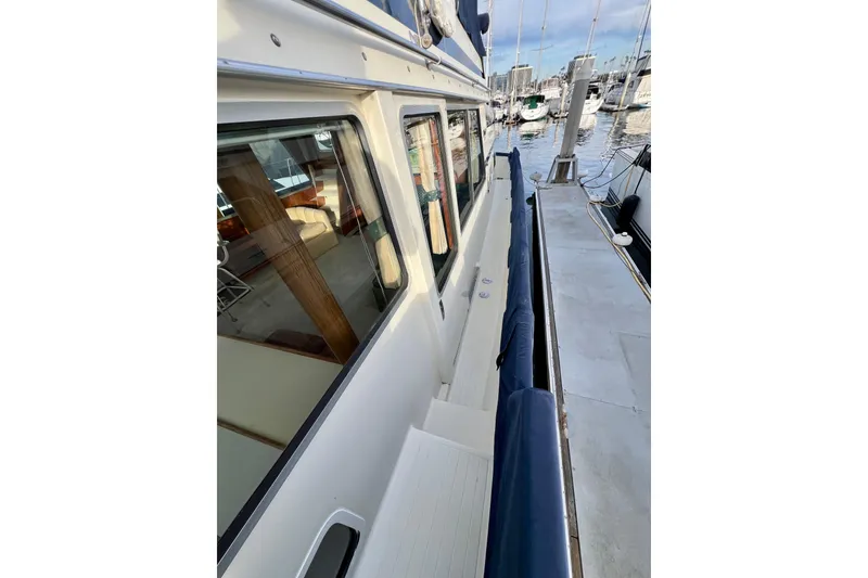 Slide: The Image of 1985 Tollycraft 48 Cockpit Motor Yacht docked, showcasing side deck and marina view. - 10