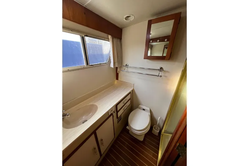 Slide: The Image of 1985 Tollycraft 48 Cockpit Motor Yacht bathroom with sink, toilet, and mirror. - 105