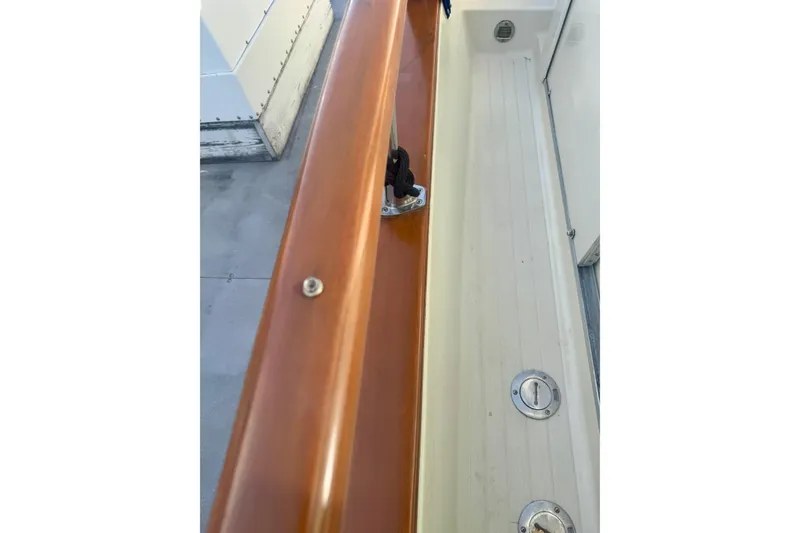 Slide: The Image of 1985 Tollycraft 48 Cockpit Motor Yacht deck with polished wood railing and cleat. - 11