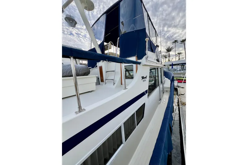 Slide: The Image of 1985 Tollycraft 48 Cockpit Motor Yacht docked, featuring sleek design and blue accents. - 18