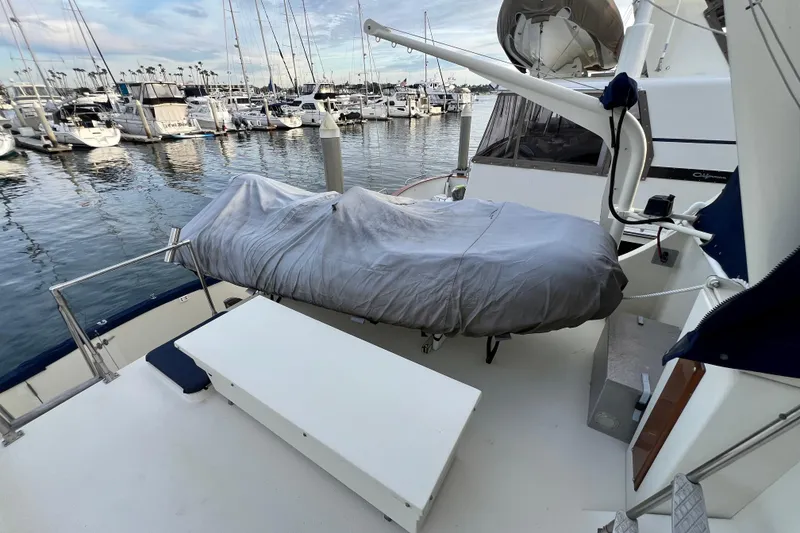 Slide: The Image of 1985 Tollycraft 48 Cockpit Motor Yacht docked, featuring covered equipment and marina view. - 21