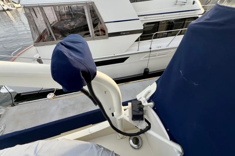 Slide: The Image of 1985 Tollycraft 48 Cockpit Motor Yacht docked, featuring covered equipment and adjacent vessel. - 22