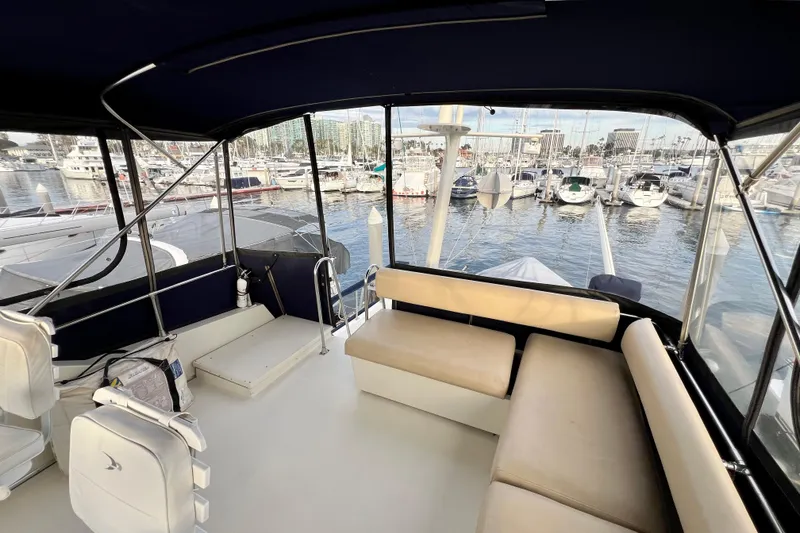 Slide: The Image of 1985 Tollycraft 48 Cockpit Motor Yacht interior with marina view, featuring seating and helm area. - 28
