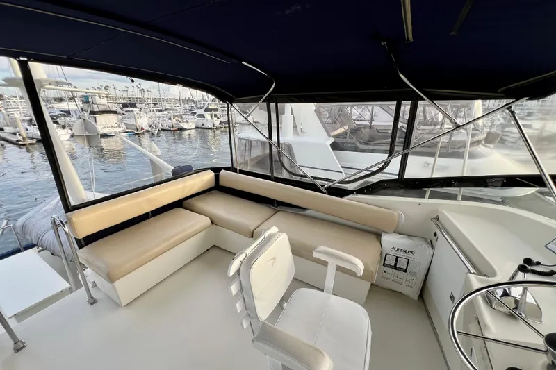 Slide: The Image of 1985 Tollycraft 48 Cockpit Motor Yacht interior with seating and helm, docked at marina. - 29