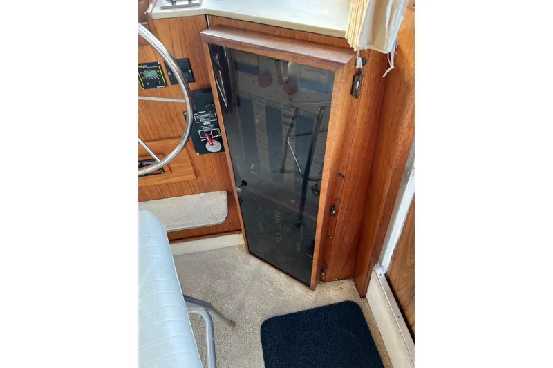 Slide: The Image of 1985 Tollycraft 48 Cockpit Motor Yacht helm with wooden paneling and steering wheel. - 52