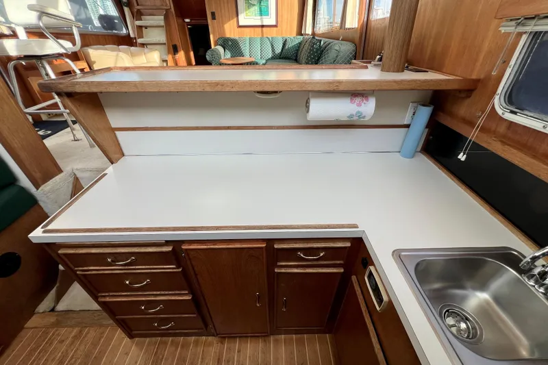 Slide: The Image of 1985 Tollycraft 48 Cockpit Motor Yacht kitchen with wooden cabinets and stainless steel sink. - 62