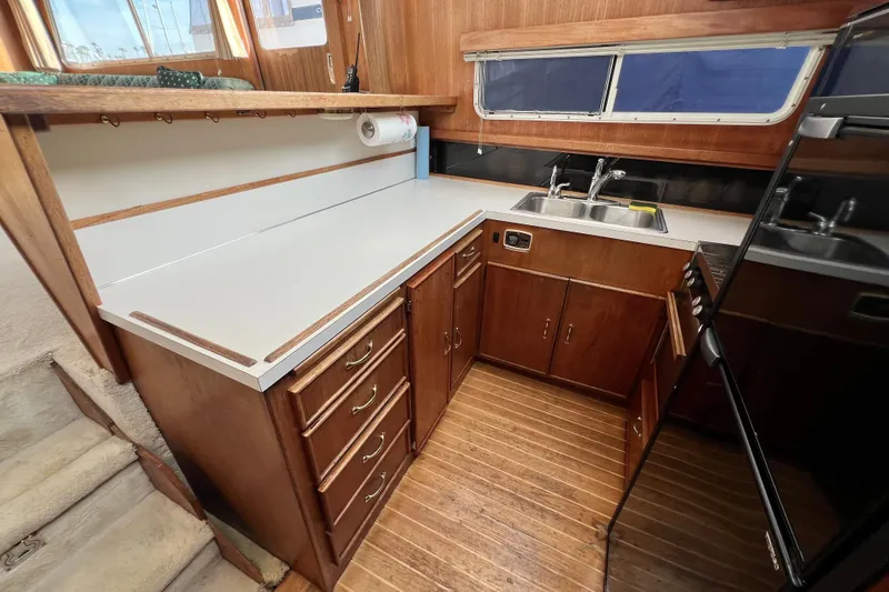 Slide: The Image of 1985 Tollycraft 48 Cockpit Motor Yacht kitchen with wooden cabinets and dual sink. - 63