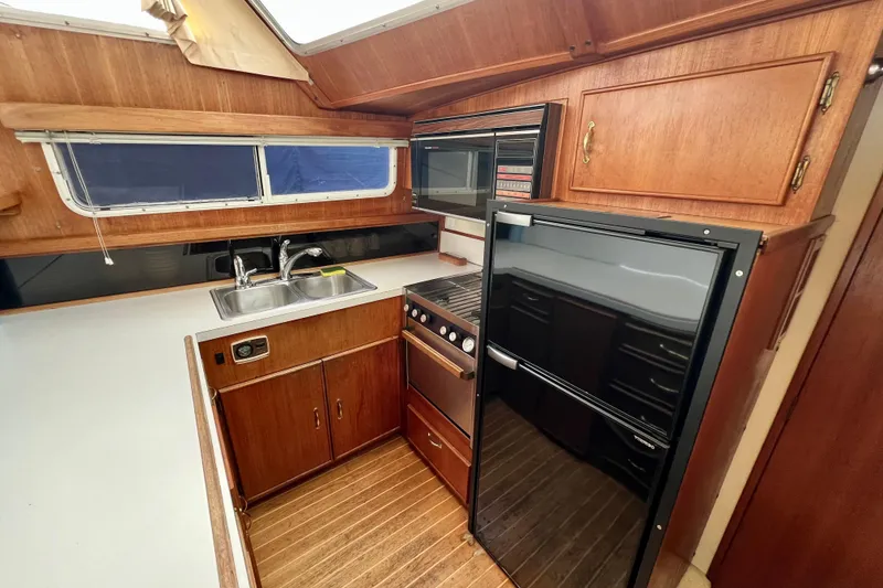 Slide: The Image of 1985 Tollycraft 48 Cockpit Motor Yacht kitchen with wood cabinetry and modern appliances. - 64