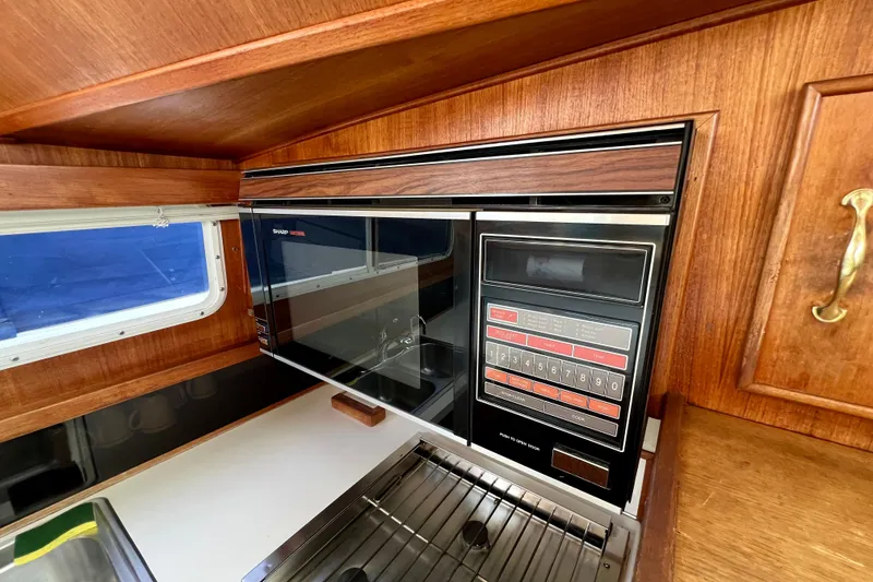 Slide: The Image of 1985 Tollycraft 48 Cockpit Motor Yacht kitchen with vintage Sharp microwave and wooden cabinetry. - 66