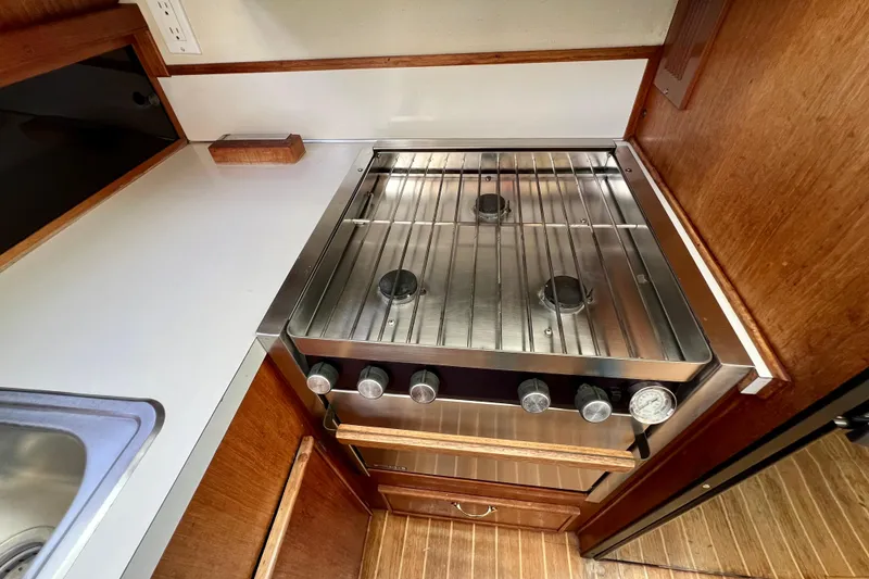 Slide: The Image of 1985 Tollycraft 48 Cockpit Motor Yacht kitchen with stainless steel stove and wooden cabinetry. - 67