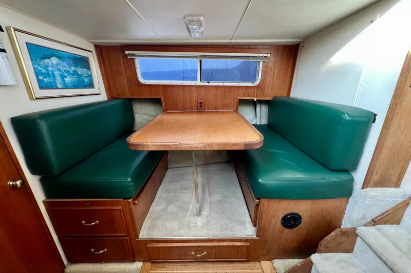 Slide: The Image of Interior of 1985 Tollycraft 48 Cockpit Motor Yacht with green cushioned seating and wooden table. - 70