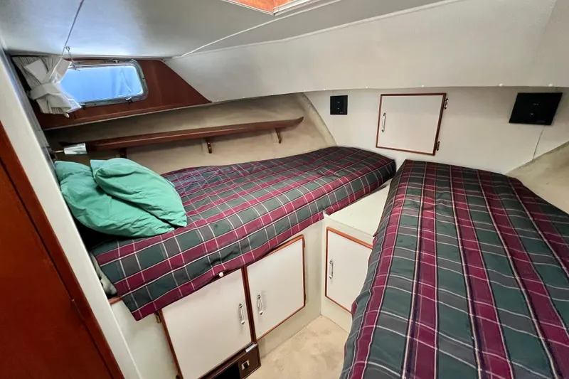 Slide: The Image of 1985 Tollycraft 48 Cockpit Motor Yacht cabin with twin beds and plaid bedding. - 74