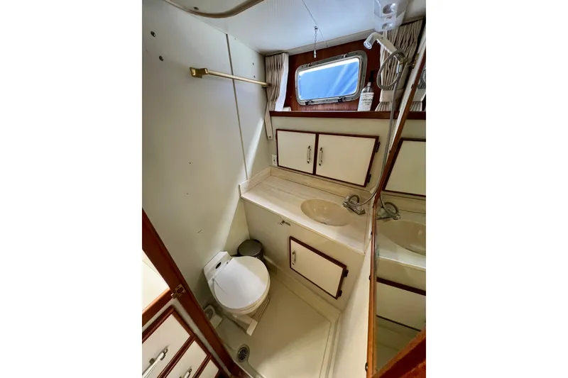 Slide: The Image of 1985 Tollycraft 48 Cockpit Motor Yacht bathroom with sink, toilet, and storage cabinets. - 79