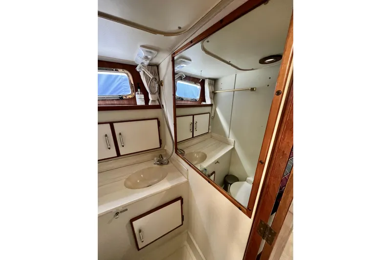 Slide: The Image of 1985 Tollycraft 48 Cockpit Motor Yacht bathroom with sink, mirror, and storage cabinets. - 80