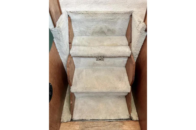 Slide: The Image of Carpeted stairs inside 1985 Tollycraft 48 Cockpit Motor Yacht, featuring wooden side panels. - 81
