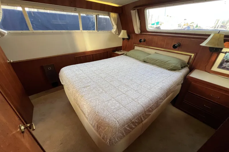 Slide: The Image of 1985 Tollycraft 48 Cockpit Motor Yacht bedroom with cozy bed and wooden interior. - 97