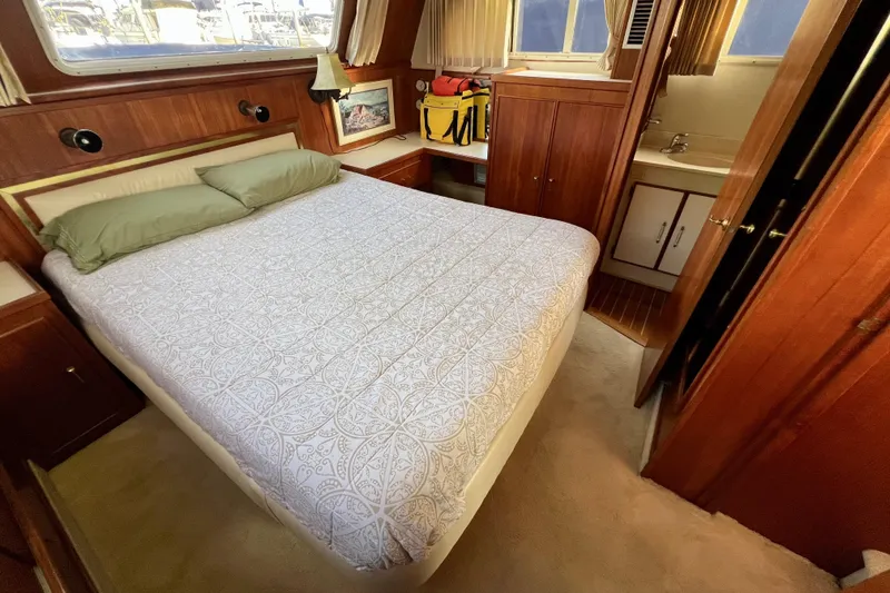 Slide: The Image of 1985 Tollycraft 48 Cockpit Motor Yacht bedroom with bed, wood paneling, and small sink area. - 98