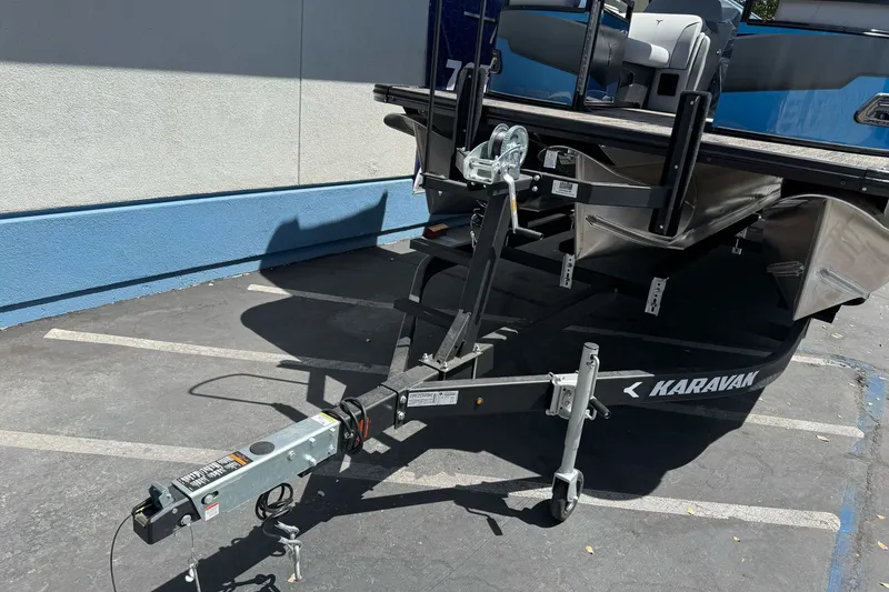 Slide: The Image of 2026 Tahoe Pontoon Sport 85 Elite Windshield 25 on Karavan trailer in parking lot. - 2