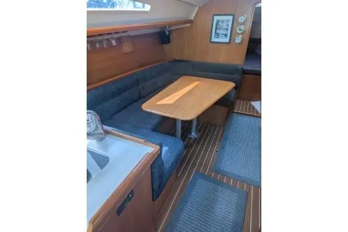 Slide: The Image of 2004 Hunter 33 sailboat interior with cozy seating and wooden table. - 16
