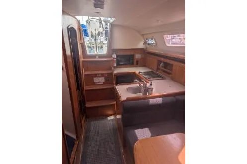 Slide: The Image of Interior of a 2004 Hunter 33 sailboat featuring a compact kitchen and seating area. - 27