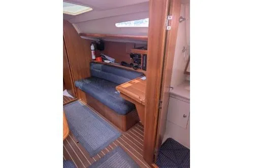 Slide: The Image of 2004 Hunter 33 yacht interior with seating, wooden cabinetry, and nautical decor. - 31