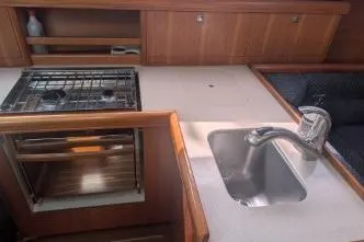 Slide: The Image of 2004 Hunter 33 yacht kitchen with stove, sink, and wooden cabinetry. - 32