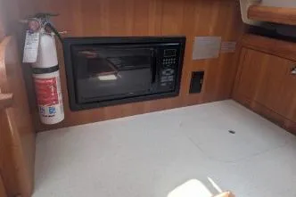 Slide: The Image of 2004 Hunter 33 yacht interior with microwave and fire extinguisher in wooden cabinetry. - 33
