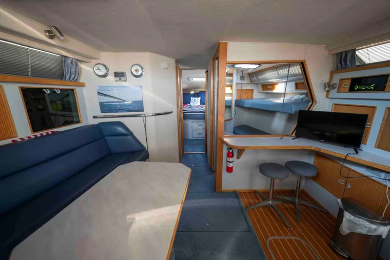 Slide: The Image of Interior of a 1991 Sea Ray 390 Express Cruiser with seating, table, and TV. - 13