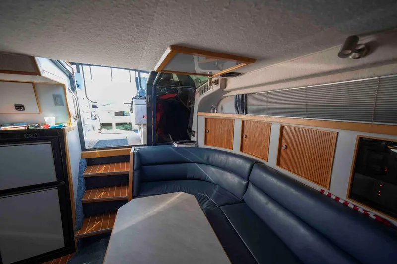 Slide: The Image of Interior of 1991 Sea Ray 390 Express Cruiser with blue seating and wooden cabinetry. - 14