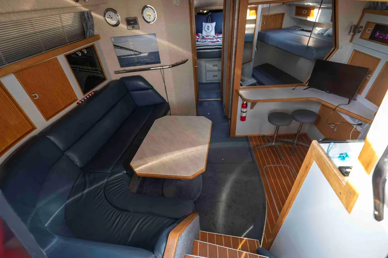 Slide: The Image of Interior of 1991 Sea Ray 390 Express Cruiser with seating, table, and modern amenities. - 16