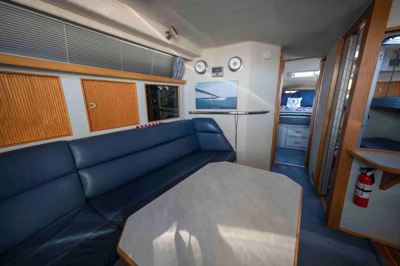 Slide: The Image of Interior of 1991 Sea Ray 390 Express Cruiser with blue seating and wooden accents. - 18