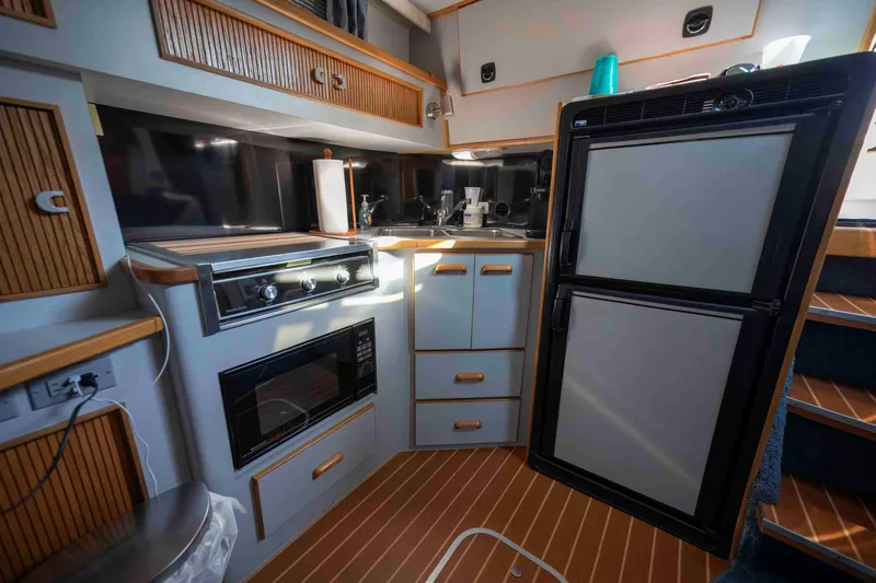 Slide: The Image of 1991 Sea Ray 390 Express Cruiser kitchen with stove, microwave, and refrigerator. - 22