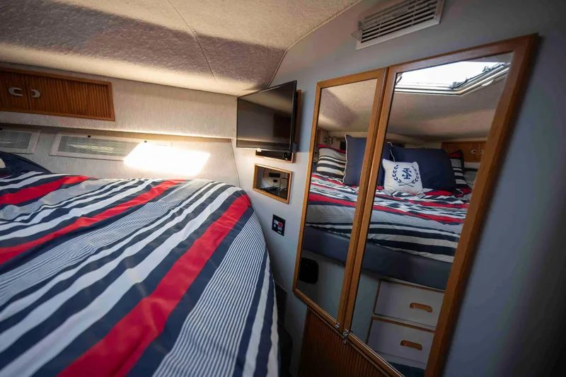 Slide: The Image of Interior of 1991 Sea Ray 390 Express Cruiser with striped bedding and mirrored closet. - 24