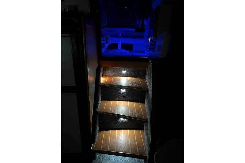 Slide: The Image of Illuminated wooden steps inside a 1991 Sea Ray 390 Express Cruiser, featuring blue ambient lighting. - 27