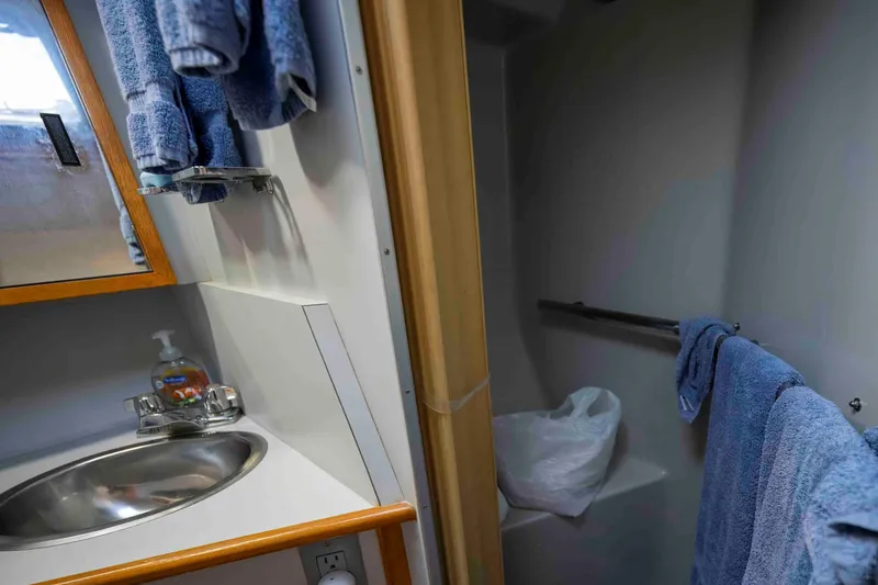 Slide: The Image of Bathroom interior of 1991 Sea Ray 390 Express Cruiser with sink and blue towels. - 28