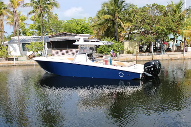 Slide: The Image of 2007 Fountain 34 Center Console boat on calm water, surrounded by tropical trees. - 2