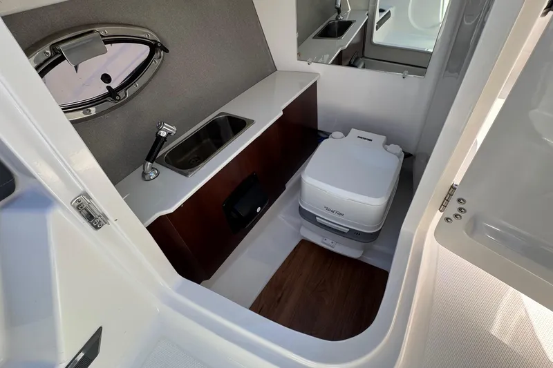 Slide: The Image of Interior of 2026 Chaparral SSX 4 boat featuring compact bathroom with sink and toilet. - 27