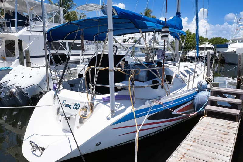 Slide: The Image of 1993 Beneteau First 38 s5 sailboat docked, featuring blue canopy and vibrant hull design. - 2