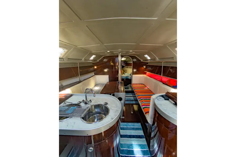 Slide: The Image of Interior of 1993 Beneteau First 38 s5 yacht, featuring cozy seating and compact kitchen area. - 9