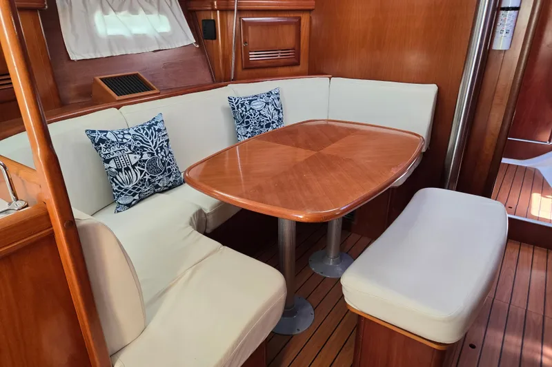 Slide: The Image of Interior of 2003 Beneteau 393 yacht with wooden table, cushioned seating, and decorative pillows. - 18