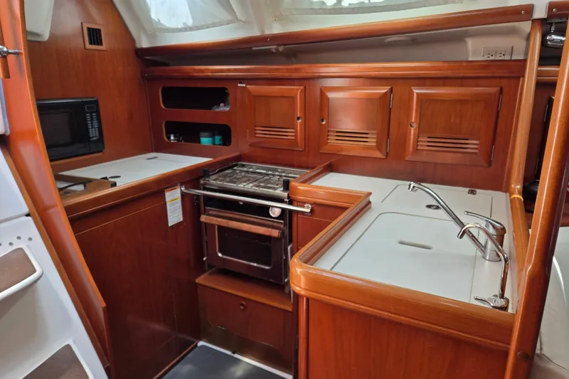 Slide: The Image of Galley kitchen in 2003 Beneteau 393 sailboat with wood cabinetry and modern appliances. - 19