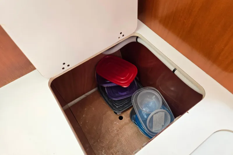 Slide: The Image of Storage compartment with plastic containers on a 2003 Beneteau 393 sailboat. - 23