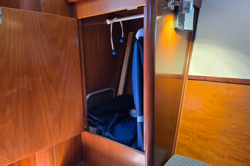 Slide: The Image of Wooden closet interior on a 2003 Beneteau 393 sailboat, featuring hanging clothes and storage. - 34
