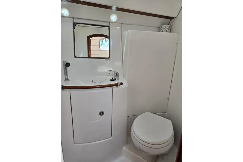 Slide: The Image of Compact bathroom in a 2003 Beneteau 393 yacht, featuring a sink, mirror, and toilet. - 37