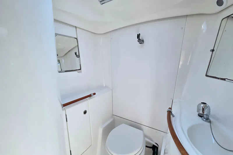 Slide: The Image of Compact bathroom in a 2003 Beneteau 393 yacht, featuring a toilet, sink, and mirrors. - 45