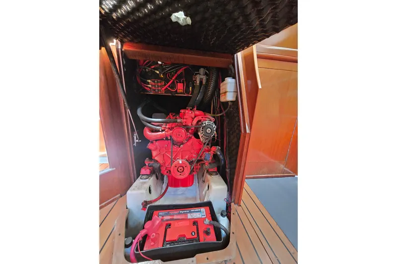 Slide: The Image of Engine compartment of a 2003 Beneteau 393 sailboat, featuring a red engine and battery. - 47